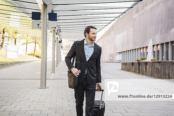Businessman on the move pushing rolling suitcase