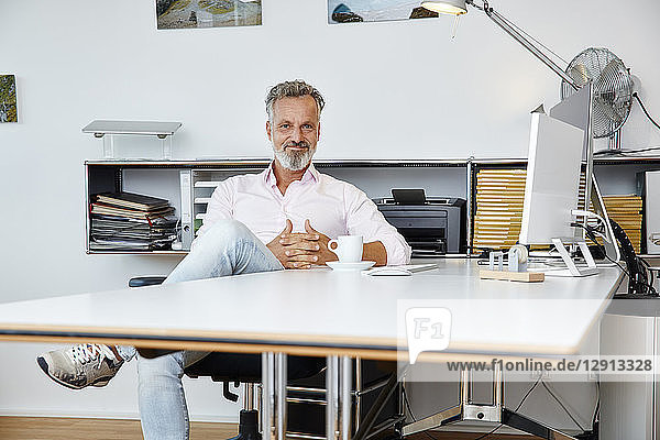 Portrait of confident businessman sitting at desk in office