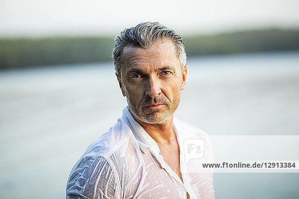 Portrait of mature man wearing wet white shirt at lake