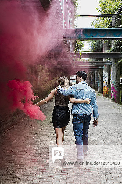 Young couple with smoke torch walking outdoors