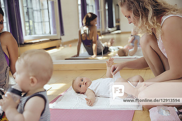 Mother changing diapers of baby in exercise room