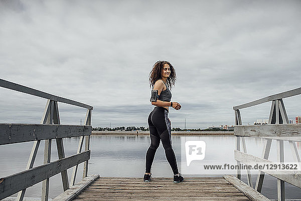 Young athletic woman standing on jetty at the riverside