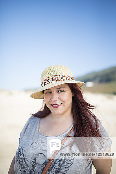 Portrait of smiling woman wearing summer hat on the beach