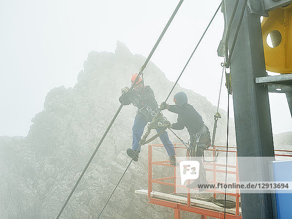 Germany  Bavaria  Garmisch-Partenkirchen  Zugspitze  installers working on steel rope of a goods cable lift