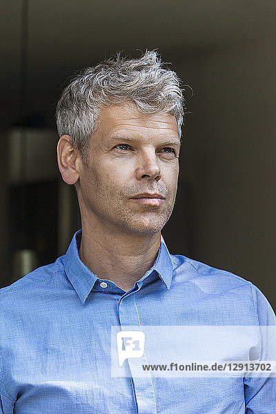 Portrait of pensive mature man with grey hair wearing blue skirt