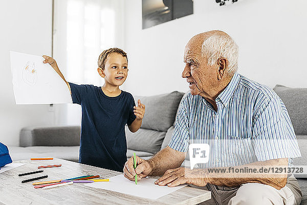 Grandfather and grandson drawing with coloured pencils in the living room