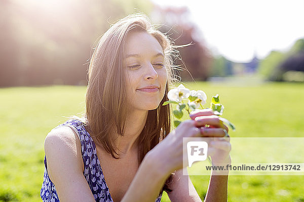 Smiling young woman in a park holding flowers