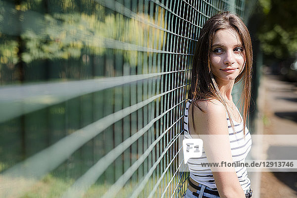 Portrait of smiling young woman standing at a fence