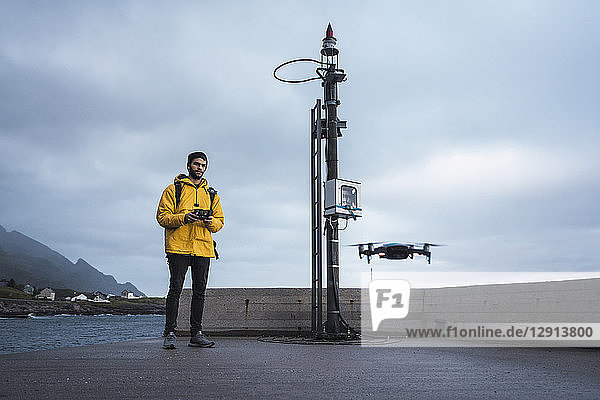 Norway  Lofoten  man standing at the coast flying a drone