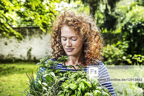 Portrait of young woman with fresh herbs in garden