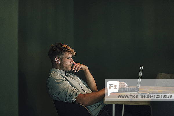 Man sitting in office  working late in his start-up company  listening music