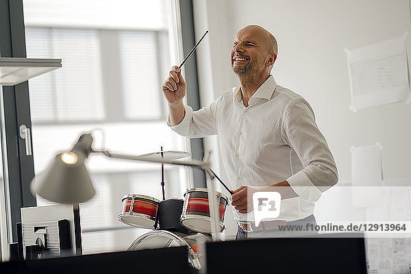 Businessman making noise with drums in his office