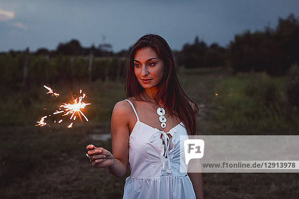 Young woman in nature  burning sparkler in the evening