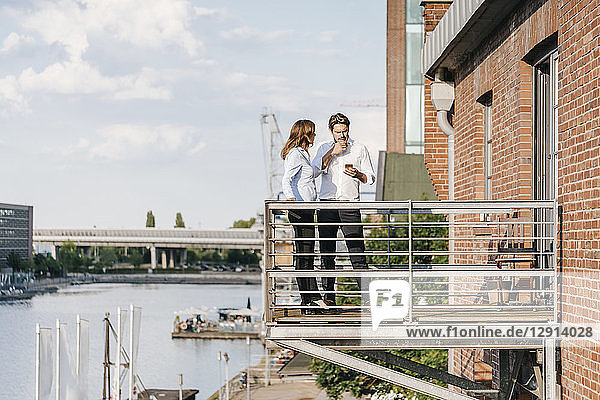 Business people standing on balcony  using smartphone