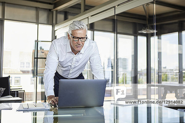 Businessman standing at desk  looking at laptop