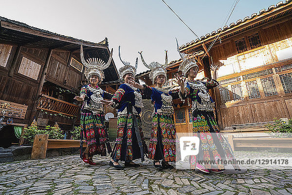 China  Guizhou  Miao women wearing traditional dresses and headdresses posing on village square