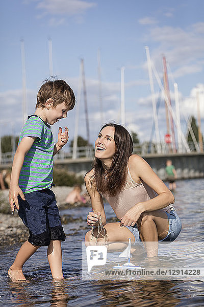 Germany  Friedrichshafen  Lake Constance  happy mother and son with toy boat at lakeshore