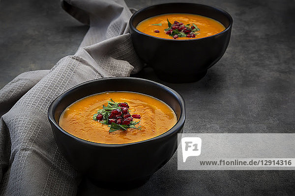 Bowl of carrot ginger coconut soup with topping of parsley and pomegranate seed