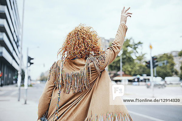 Redheaded woman hailing a taxi in the street