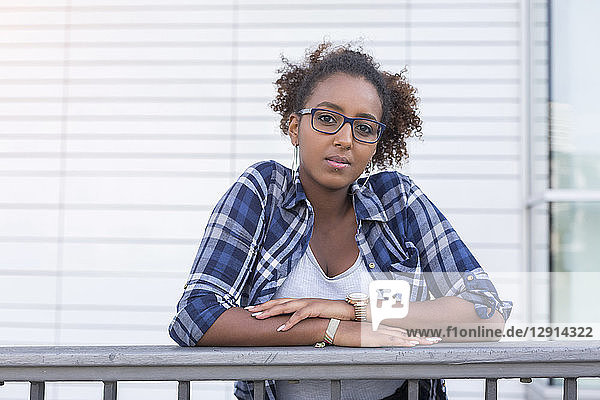Portrait of young woman wearing glasses leaning on railing