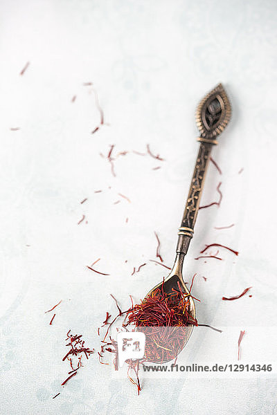 Spoon with saffron threads on light ground