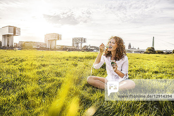 Germany  Cologne  portrait of happy young woman eating jelly on meadow