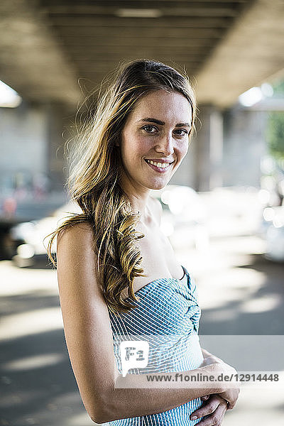 Portrait of smiling long-haired woman standing at underpass