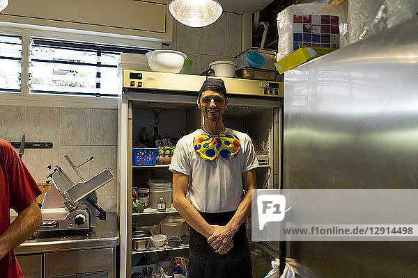 Portrait of funny pizza baker wearing clown's bow tie in kitchen