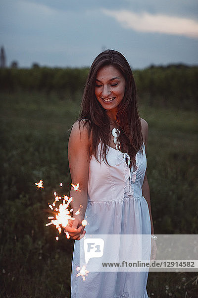 Young woman in nature  burning sparkler in the evening