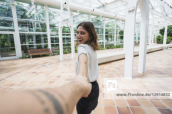 Woman holding hand ofc man in greenhouse
