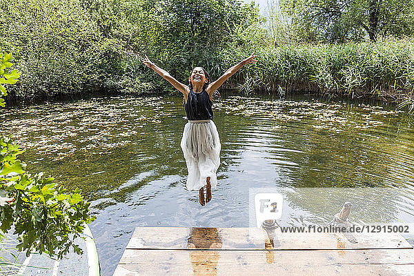 Carefree girl jumping into pond