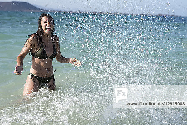 Happy carefree young woman splashing in the sea