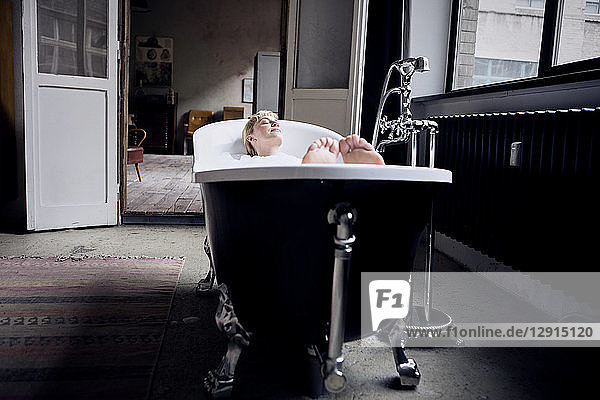 Woman taking bubble bath in a loft