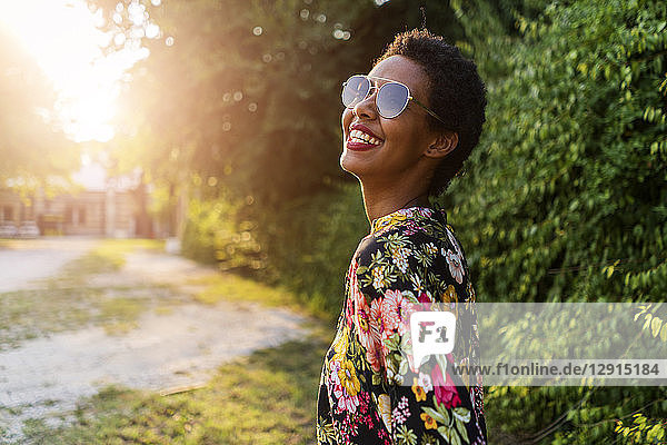 Happy young woman wearing sunglasses outdoors at sunset