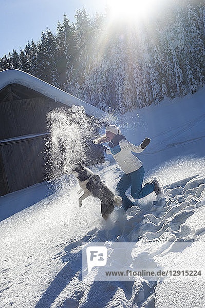 Austria  Altenmarkt-Zauchensee  happy young woman playing with dog in snow