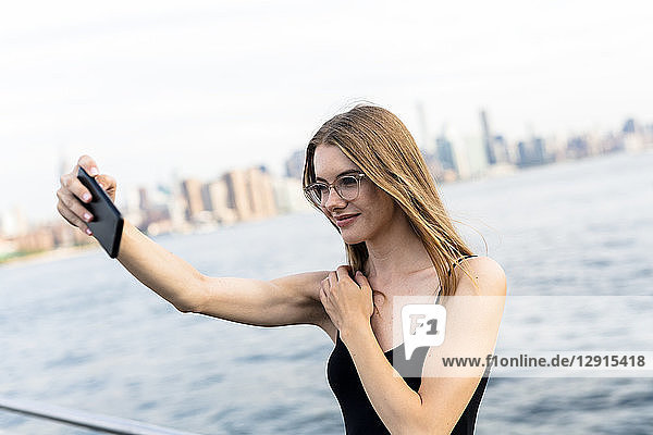 Young woman taking selfies at East River
