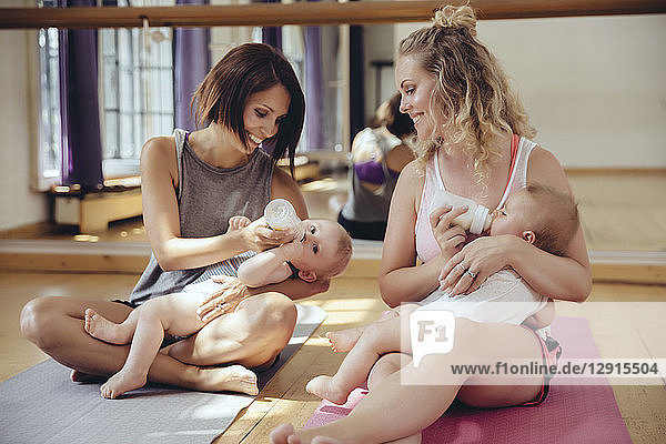 Two mothers bottle-feeding their babies in exercise room
