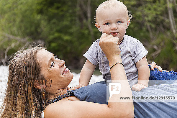 Happy mother playing with baby boy outdoors in nature