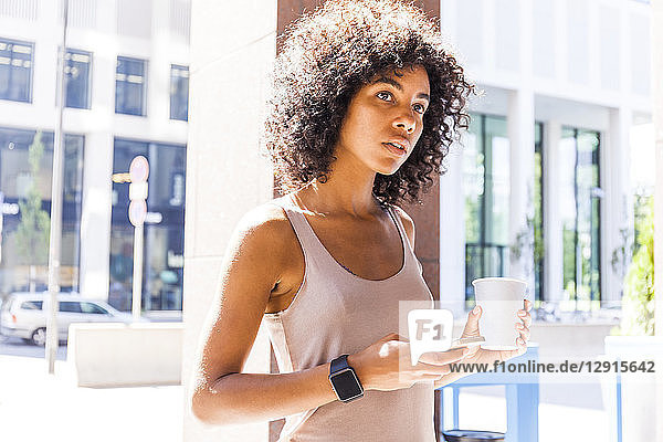 Portrait of pensive young woman with coffee to go and cell phone