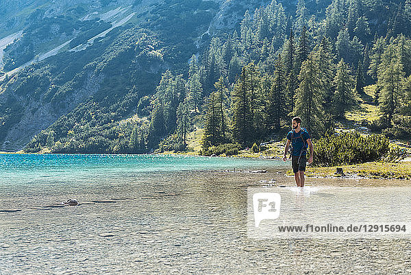 Austria  Tyrol  Hiker at Lake Seebensee walking ankle deep in water