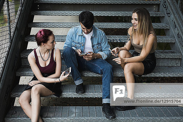 Friends relaxing on stairs outdoors using cell phones