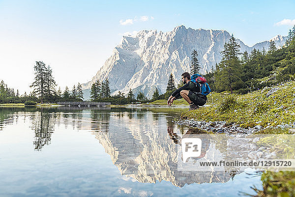 Austria  Tyrol  Hiker taking a break  crouching by the lake