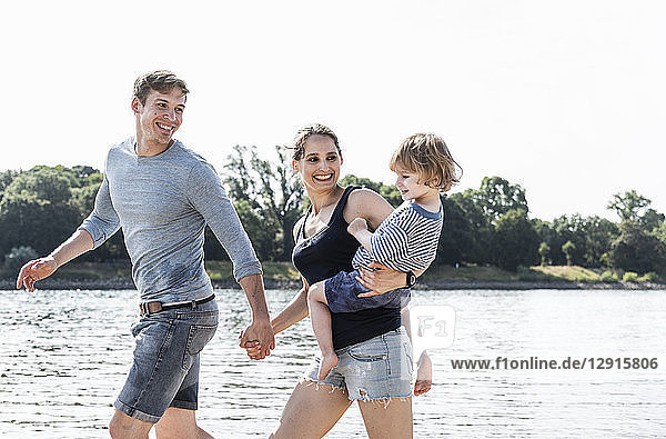 Happy family walking at the riverside on a beautiful summer day