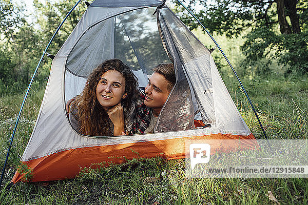Young couple camping in nature  lying in tent  taking a break
