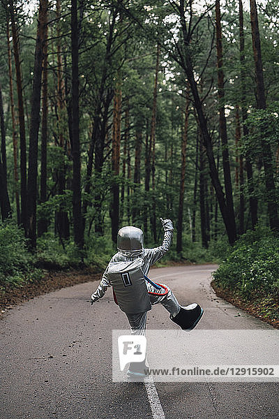 Spaceman exploring nature  standing on road in foreat