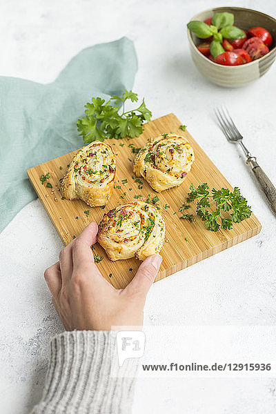 Woman's hand taking sticky bun with feta  cream cheese  bacon and parsley