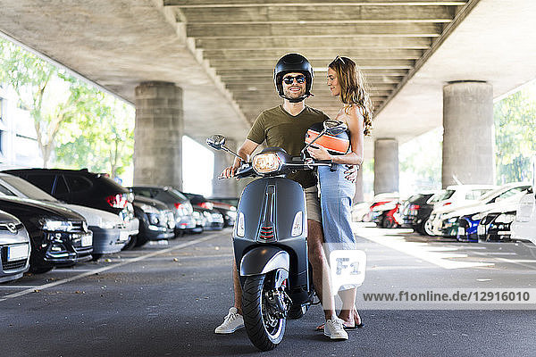 Happy couple with motor scooter at underpass