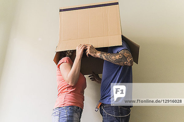 Couple with heads together in cardboard box at new home