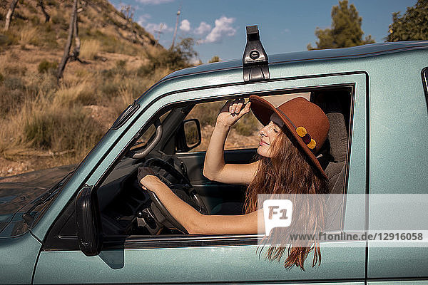 Smiling young woman wearing a hat sitting in a car
