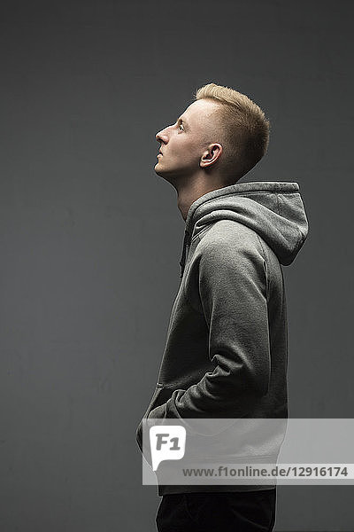 Profile of blond young man wearing grey hooded jacket